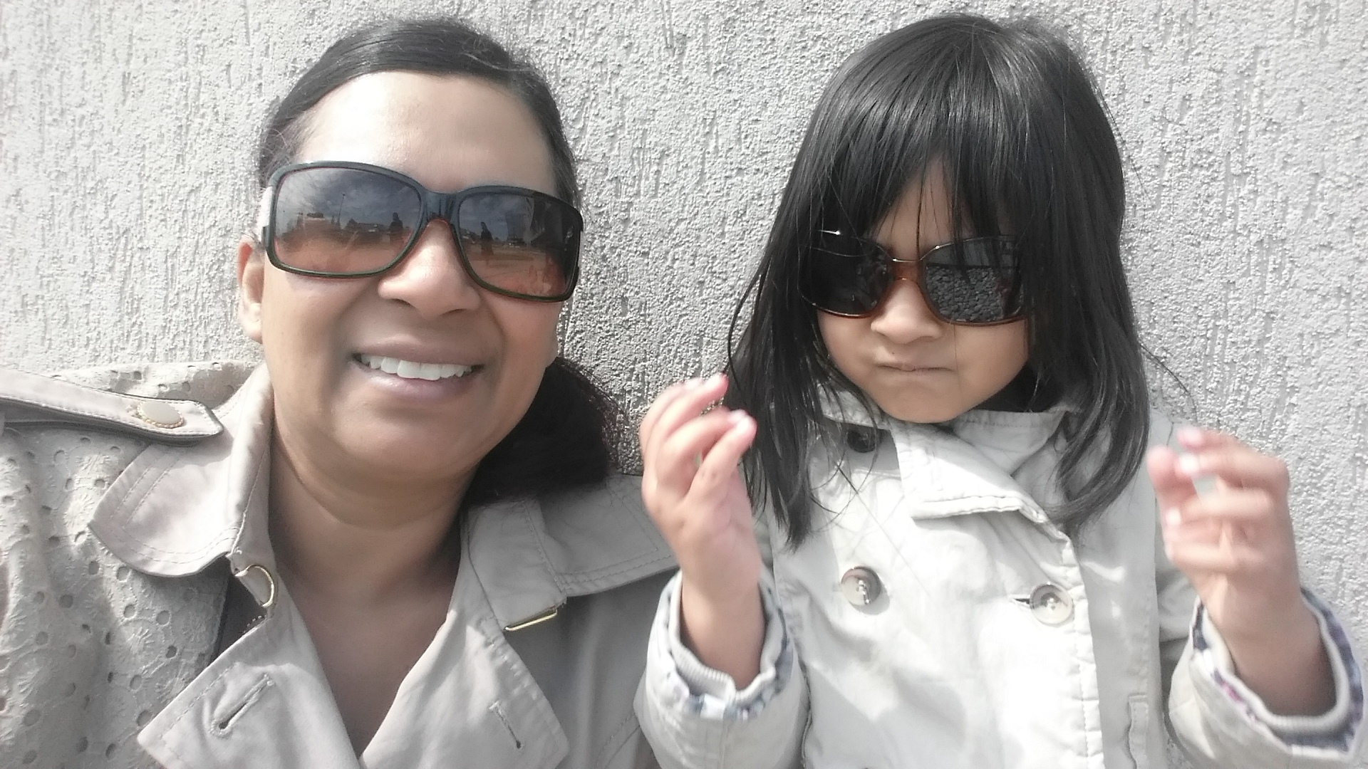 Woman and child wearing trench coats and dark glasses